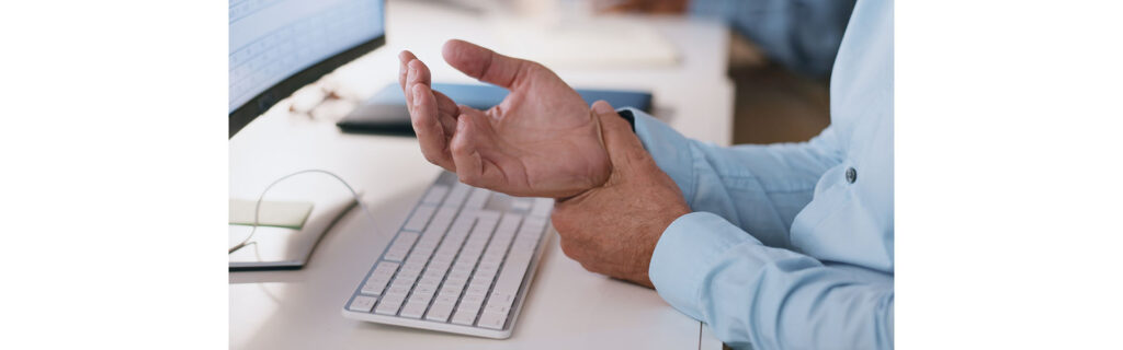 Businessman, hands and wrist in joint pain from injury, overworked or carpal tunnel syndrome at office. Closeup of man or employee with arthritis, ache or inflammation of palm on desk at workplace.